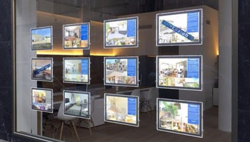 Escaparate de agencia inmobiliaria con anuncios de viviendas en venta y alquiler